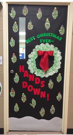 a door decorated with christmas wreaths and handwritten words on black paper, which reads best christmas ever hands down