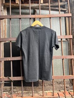 a black shirt hanging on a metal bar in front of an old window with bars