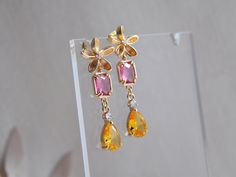 "Flower Earrings // Floral Drop Earrings // Pink and Yellow Earrings // Summer Earrings // Bridal Earrings // Wedding Earrings // Boho Statement Earrings Make a statement with these unique floral drop earrings created with pretty pink and yellow! The flower earrings accented with a tiny cubic zirconia for a dash of sparkle. Secured to them are beautiful faceted magenta pink rectangles set into gold plated bezels. Suspended from the flower earrings are sparkling yellow teardrops for a pop of colo Elegant Yellow Dangle Flower Earrings, Elegant Yellow Flower Earrings For Wedding, Yellow Flower Drop Earrings For Wedding, Yellow Ear Wire Earrings For Wedding, Yellow Dangle Earrings For Wedding, Yellow Flower Earrings For Wedding, Yellow Earrings With Ear Wire For Wedding, Yellow Wedding Earrings With Ear Wire, Pink Flower Earrings