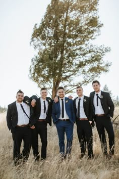 a group of men standing next to each other in a field with a tree behind them