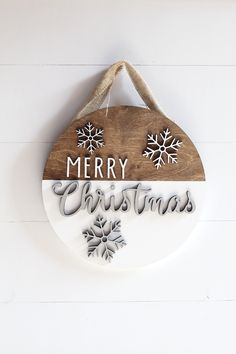 a wooden sign hanging on the side of a white wall with snowflakes