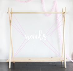 a wooden frame with the word nails painted on it in front of a white wall