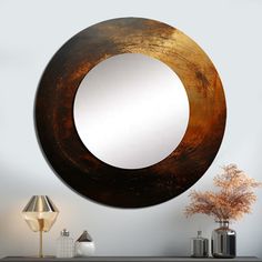 a round mirror hanging on the wall next to a lamp and table with vases