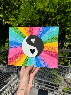 a person holding up a card with a yin - yang symbol painted on the front