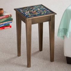 a small wooden table sitting on top of a carpeted floor next to a pile of books