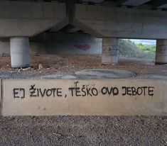 graffiti on the side of a concrete wall under a bridge