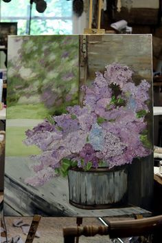 a painting of purple flowers in a bucket on an easel