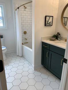 a bathroom with white tile and green cabinetry is shown in this view from the doorway