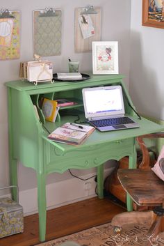 a laptop computer sitting on top of a green desk next to a chair and ottoman