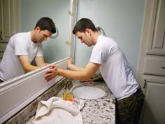 two men are looking at their reflection in the mirror