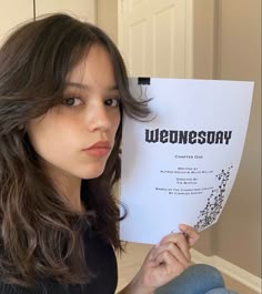 a woman holding up a paper with the words wednesday on it