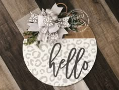 a wooden sign with the word hello on it and a bow hanging from it's side