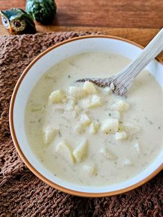 a white bowl filled with soup on top of a wooden table next to a spoon