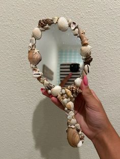 a hand holding a mirror with seashells on it