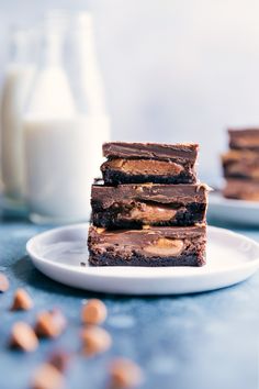 three pieces of chocolate peanut butter brownie stacked on top of each other next to a glass of milk