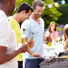 three men grilling hot dogs and drinking beer at an outdoor bbq party with friends