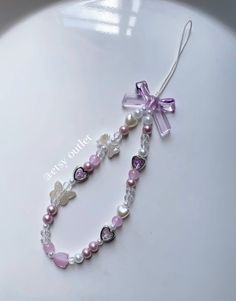 a white plate topped with a pink and purple beaded necklace