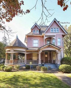 a large pink house sitting on top of a lush green field