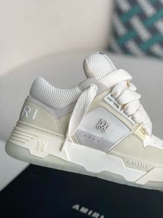 Step into effortless style with these AMIRI MA-1-inspired sneakers in a clean and contemporary beige and white colorway. Crafted with premium materials, these high-top sneakers capture the essence of AMIRI's signature aesthetic. The bold silhouette, featuring an exaggerated sole and signature details like the AMIRI logo on the side and tongue, exudes confidence and individuality. Experience the perfect fusion of comfort, quality, and head-turning style. Your order arrives in a branded shoe box, Beige High-top Sneakers With Contrast Sole For Streetwear, Cream High-top Sneakers With Contrast Sole For Streetwear, Cream High-top Sneakers With Textured Sole For Streetwear, Sporty Cream High-top Sneakers With Contrast Sole, Luxury High-top Sneakers With Textured Sole For Streetwear, Designer Low-top Cream Sneakers, Luxury Low-top Cream Sneakers, Beige High-top Sneakers With Rubber Sole For Streetwear, Designer Cream Low-top Sneakers