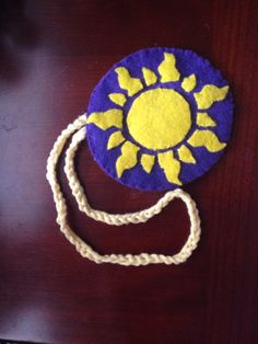 a purple and yellow hat sitting on top of a wooden table next to a rope