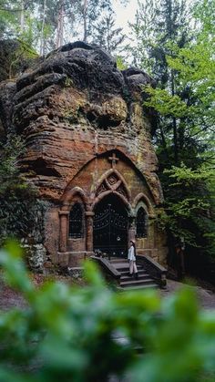 a person standing in front of a stone building with stairs leading up to the entrance