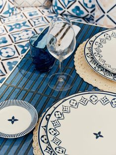 blue and white plates on a patterned table cloth with wine glass in the foreground