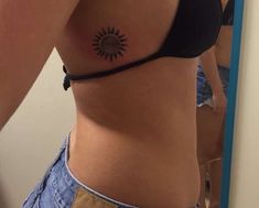 a woman with a sun tattoo on her stomach and side view mirror in the background