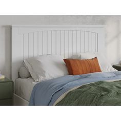 a bed with white headboard and pillows on top of it, next to a night stand