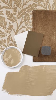 some paint samples and a brown wallpaper next to a cup of coffee on a table