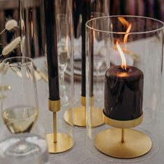 two candles sitting on top of a table next to wine glasses and other items in front of them