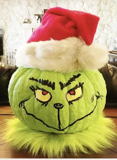 a green grin face pumpkin with a santa hat on