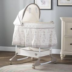 a white baby crib sitting on top of a wooden floor next to a dresser