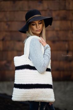 a woman wearing a hat and carrying a white crocheted bag with black stripes