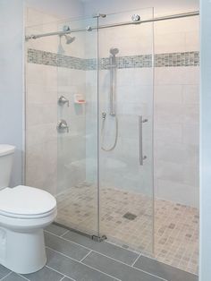 a white toilet sitting next to a shower in a bathroom under a skylight and tiled floor