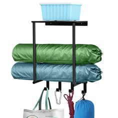 three bags and two umbrellas are hanging on a rack next to a sleeping bag