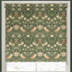 a window with an ornate green and orange roman blind