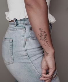 a woman with a flower tattoo on her left arm and right hand behind her back