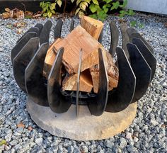 a fire pit made out of metal and wood sitting on top of gravel covered ground