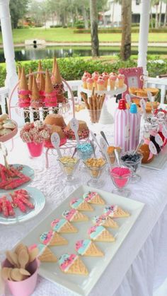 a white table topped with lots of desserts and snacks on top of it's own