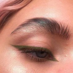 a woman's eye with green eyeshadow and long lashes, close up