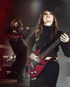 two women are playing guitars on stage