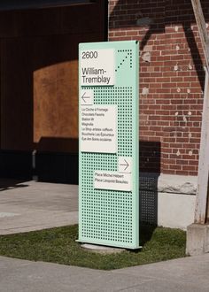 a sign on the sidewalk in front of a brick building