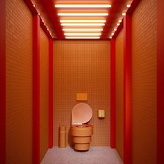 a toilet in a room with red walls and orange tiles on the wall, along with two stools