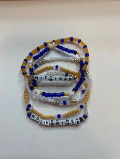 Set of five University of Michigan handcrafted beaded bracelets celebrating college spirit! Each bracelet showcases vibrant school colors and is personalized with your college's name. Perfect accessory to flaunt your school pride or a thoughtful gift. Embrace your college journey with these stylish and meaningful bracelets! Gameday Bracelets, School Spirit Beaded Bracelets With Letter Beads For Gifts, School Spirit Beaded Bracelet With Letter Beads As Gift, School Spirit Letter Beads Bracelets Gift, Personalized Team Spirit Beaded Bracelets For Gift, School Spirit Jewelry With Letter Beads For Gifts, Multicolor Personalized Team Spirit Beaded Bracelets, Personalized Multicolor Team Spirit Beaded Bracelets, Personalized Multicolor Beaded Bracelets For Team Spirit