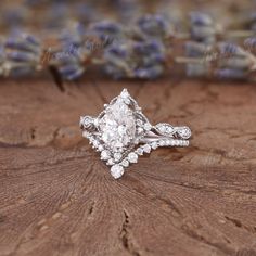 a diamond ring sitting on top of a piece of wood next to lavender flowers in the background