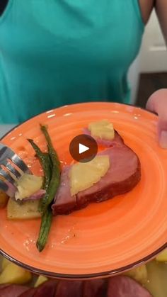 a person holding an orange plate with food on it and a fork in the middle