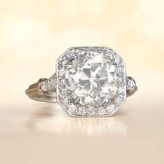 an old - fashioned engagement ring with a cushion cut diamond surrounded by pave diamonds