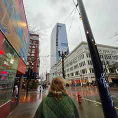 a woman is walking down the street on a rainy day