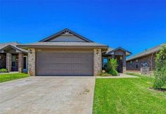 a house that is in the grass with a driveway and two garages on each side