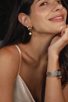 a woman with her hand on her chin and looking up at the sky while wearing two bracelets